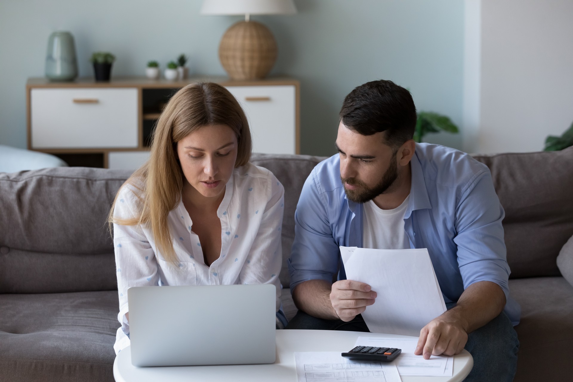 Serious focused millennial couple analyzing household budget